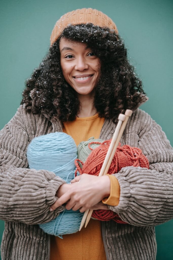 woman holding yarns nd knitting needles