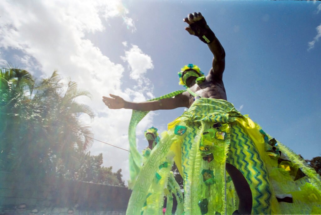 stilt walker in green crop over bands barbados