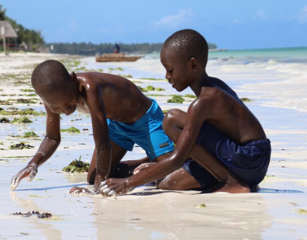 two black boys digging in the sand at a beach