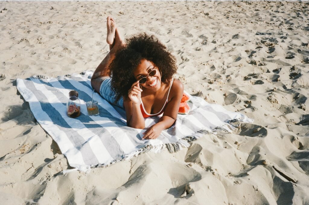 photo of woman in sunglasses laying on a towel on the beach