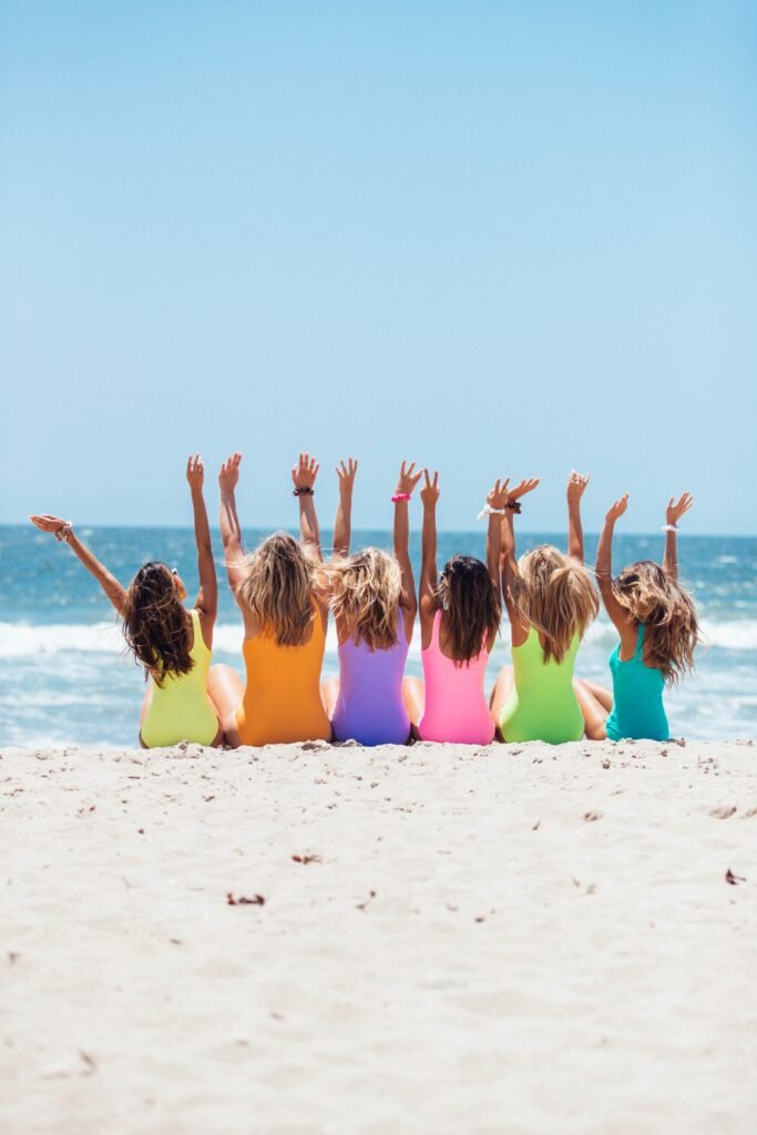 Photo of six little girls sitting on the beach facint the ocean